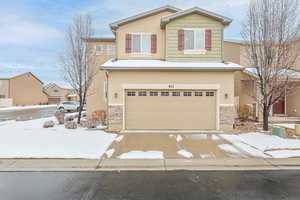 View of front of property with stone siding, stucco siding, concrete driveway, and a garage