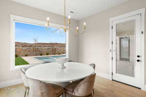 Dining room with visible vents, light wood-style flooring, baseboards, and an inviting chandelier