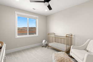 Bedroom with visible vents, a crib, baseboards, carpet, and a ceiling fan