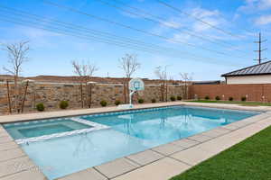 View of pool featuring a water slide, a fenced backyard, and a pool with connected hot tub