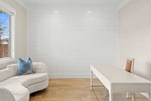 Office area featuring light wood finished floors, plenty of natural light, wooden walls, and ornamental molding