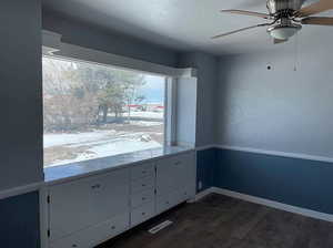 Unfurnished room with visible vents, baseboards, a ceiling fan, and dark wood-style flooring