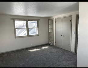Unfurnished bedroom featuring visible vents, a textured ceiling, a closet, carpet floors, and baseboards
