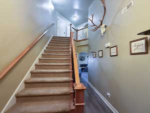 Stairway featuring wood finished floors, visible vents, baseboards, a high ceiling, and arched walkways