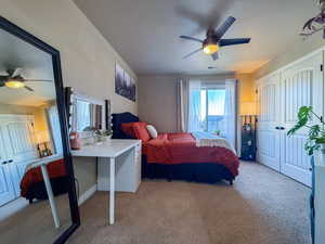 Bedroom with a ceiling fan, light colored carpet, and visible vents