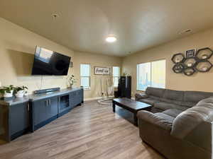 Living area featuring a wealth of natural light, visible vents, baseboards, and light wood-style floors