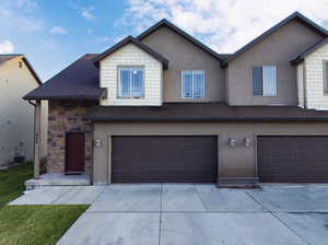 View of front facade featuring stucco siding, concrete driveway, and a garage
