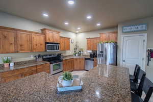 Kitchen with recessed lighting, brown cabinets, appliances with stainless steel finishes, and a sink