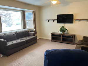 Living room with light colored carpet, baseboards, and a ceiling fan
