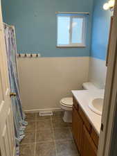 Full bathroom featuring visible vents, toilet, vanity, tile patterned floors, and tile walls