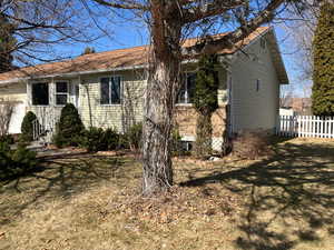 View of side of home featuring fence and a lawn