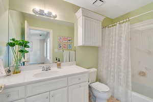 Full bath with visible vents, toilet, vanity, and shower / bathtub combination with curtain