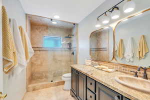 Full bath featuring vanity, toilet, and tiled shower