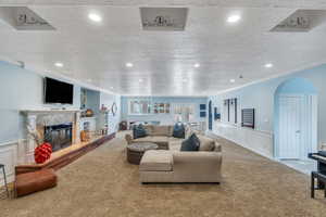 Living area featuring recessed lighting, arched walkways, a tile fireplace, crown molding, and carpet flooring