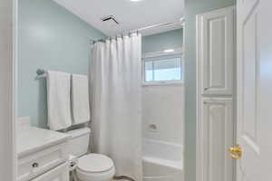 Full bathroom with vanity, visible vents, shower / bath combination with curtain, a textured ceiling, and toilet
