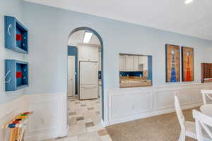 Interior space with arched walkways, a decorative wall, wainscoting, and crown molding