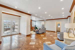 Living room with crown molding, recessed lighting, french doors, and baseboards