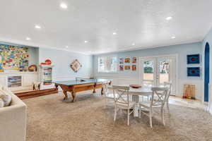 Recreation room with ornamental molding, a textured ceiling, recessed lighting, french doors, and wainscoting