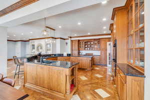 Kitchen featuring a large island, open shelves, a sink, a breakfast bar area, and brown cabinetry