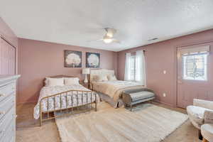 Carpeted bedroom featuring visible vents, baseboards, a textured ceiling, and a ceiling fan