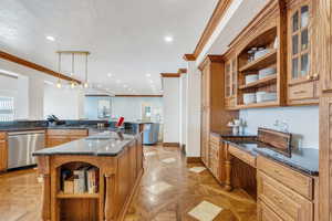 Kitchen featuring crown molding, dishwasher, dark stone counters, a textured ceiling, and open shelves