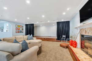 Living room featuring a textured ceiling, recessed lighting, arched walkways, carpet flooring, and a premium fireplace