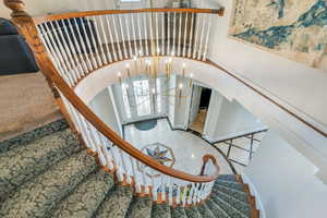 Stairs with an inviting chandelier and arched walkways