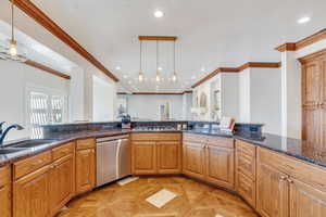 Kitchen featuring a sink, dark stone countertops, recessed lighting, stainless steel appliances, and hanging light fixtures