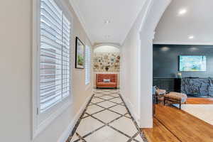 Hallway featuring baseboards, ornate columns, recessed lighting, arched walkways, and crown molding