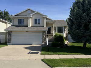 Multi-level home with stone siding, concrete driveway, a two car attached garage, a front lawn, and stucco siding