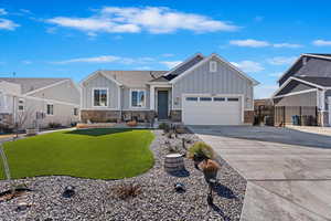 View of front of home featuring a front lawn, fence, board and batten siding, concrete driveway, and an attached garage