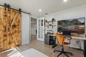 Office with baseboards, visible vents, recessed lighting, a barn door, and light wood-type flooring
