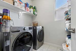 Laundry area featuring visible vents, baseboards, washing machine and dryer, light tile patterned floors, and laundry area