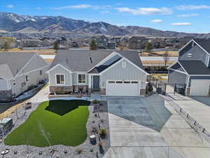 View of front facade with a mountain view, board and batten siding, driveway, and fence