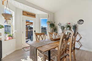 Dining space featuring vaulted ceiling, baseboards, and light wood finished floors
