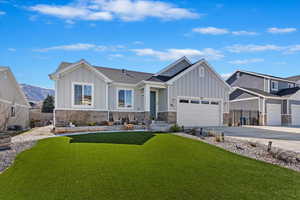 View of front of house featuring a front lawn, driveway, board and batten siding, and stone siding