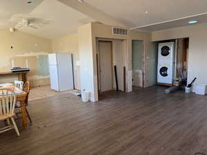 Dining area featuring visible vents, stacked washer and dryer, wood finished floors, ceiling fan, and vaulted ceiling