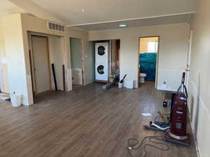 Unfurnished living room with visible vents, lofted ceiling, stacked washer and clothes dryer, and wood finished floors