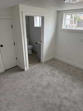 Unfurnished bedroom featuring carpet floors, baseboards, a textured ceiling, and connected bathroom
