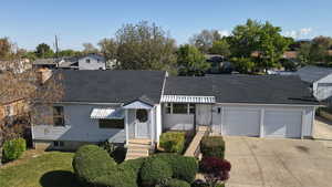View of front of property featuring driveway, a front yard, roof with shingles, a residential view, and an attached garage