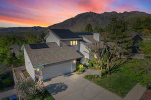 Exterior space with a garage, stucco siding, roof mounted solar panels, a mountain view, and concrete driveway