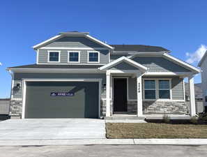 View of front of house featuring stone siding and concrete driveway