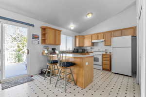 Kitchen with under cabinet range hood, open shelves, white appliances, a peninsula, and light floors