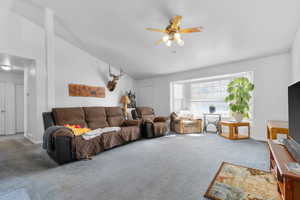 Living room featuring high vaulted ceiling, carpet flooring, baseboards, and ceiling fan