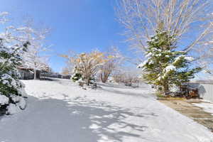 Yard layered in snow featuring fence