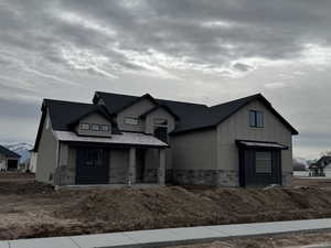 View of front of property featuring stone siding, covered porch, and board and batten siding