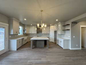 Kitchen featuring a center island, recessed lighting, an inviting chandelier, wood finished floors, and open shelves