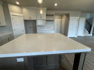 Kitchen with recessed lighting, light stone countertops, wood finished floors, and a center island