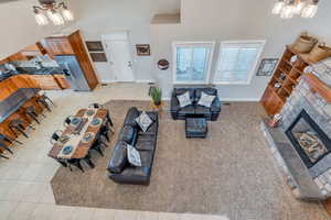 Living room with light tile patterned floors, baseboards, a towering ceiling, a glass covered fireplace, and a notable chandelier