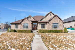 View of front of home with stucco siding, stone siding, roof with shingles, and fence